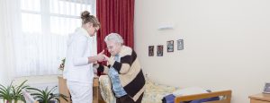 eine junge Pflegerin hilft einer Bewohnerin beim Hinstellen