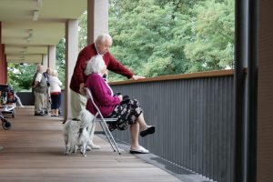 Bewohner der Seniorenwohnanlage schauen vom Balkon in den Garten